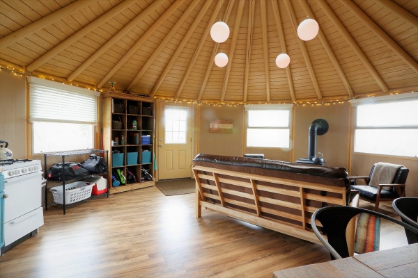 A nicely finished interior of a 16-Wall Yurt Cabin with wood floors and a stove.
