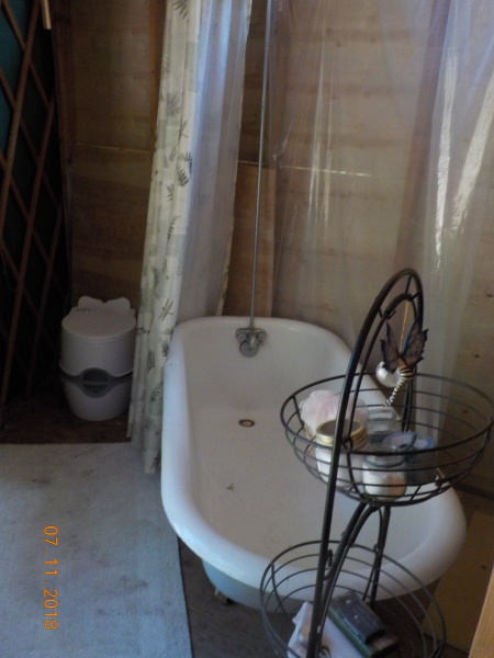 Bathroom with clawfoot tub and temporary porta-potty. Leaning towards getting a composting toilet.