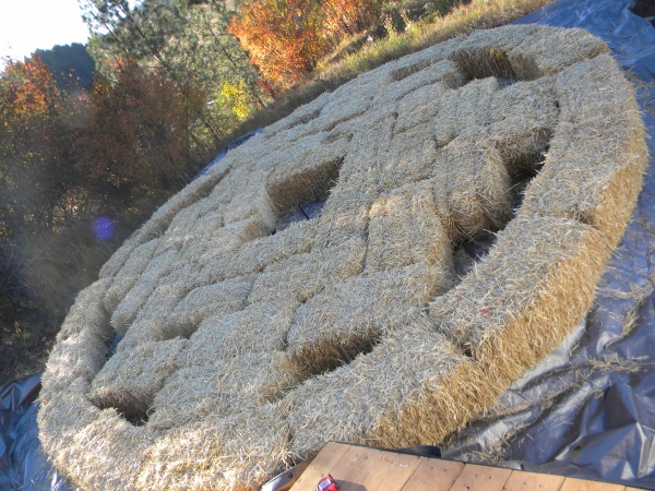 Complete bales placed on tarp. Ground was roughly leveled, then gravel placed on it, compacted, & leveled.