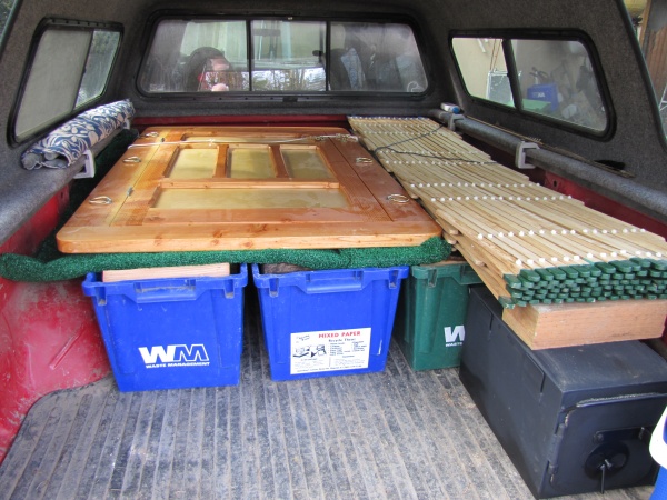 Ger in the truck heading out camping in Oregon's High Desert, door, and walls on top of bins of firewood, stove, and tools'