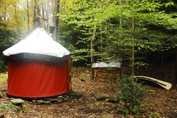 Surely Handmade Yurts - 'Secluded Forest' 10' diameter.  Showing wide view with canoe and wood pile.