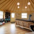 A nicely finished interior of a 16-Wall Yurt Cabin with wood floors and a stove.